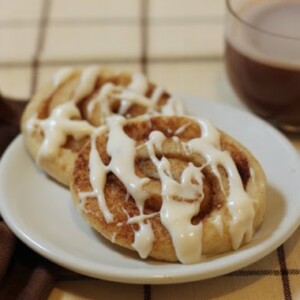 2 Cinnamon Roll Sugar Cookies on a white plate.