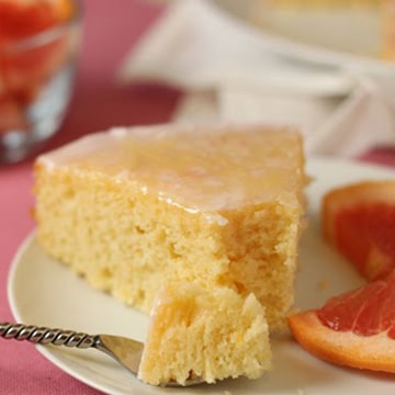 A slice of Pink Grapefruit Cake on a small plate with a bite removed.