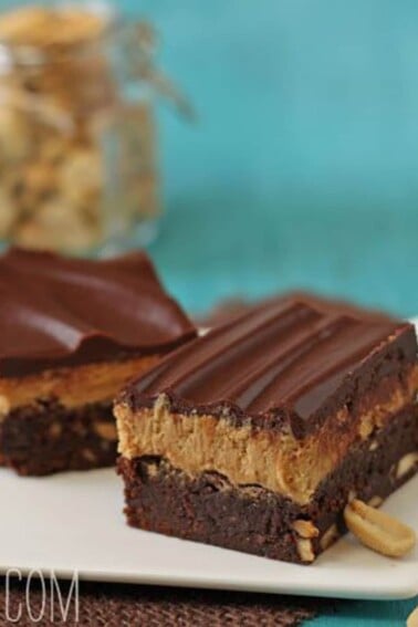 2 Layered Peanut Butter Brownies on a square white plate.