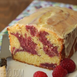 Passion Fruit Pound Cake on a long rectangular white plate next to a knife and raspberries.