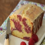 Passion Fruit Pound Cake on a white rectangular try next to a knife and raspberries.