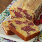 Passion Fruit Pound Cake on a white rectangular try next to a knife and raspberries.