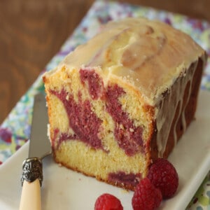 Passion Fruit Pound Cake on a white rectangular try next to a knife and raspberries.