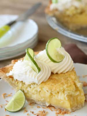 Slice of Lime-Coconut Pie on a white plate with a bite removed.