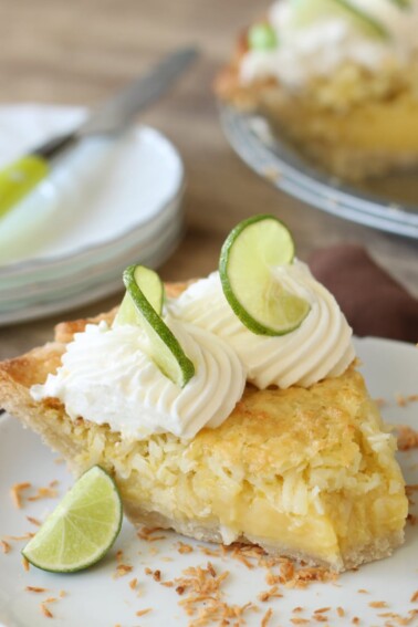 Slice of Lime-Coconut Pie on a white plate with a bite removed.