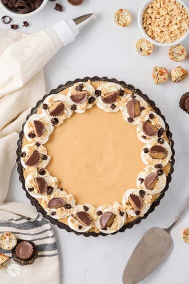 Top view of a Peanut Butter Chocolate Pie on a white surface next to peanut butter cups.
