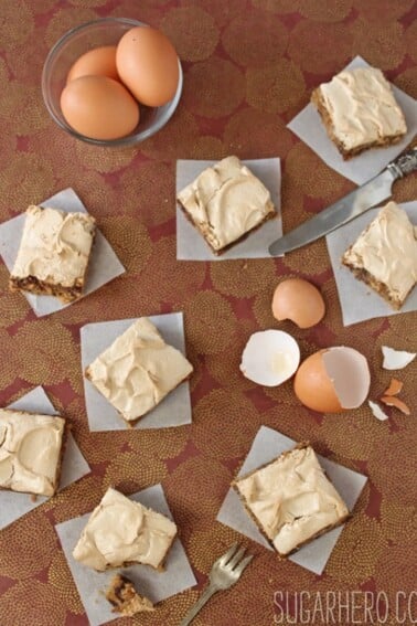 8 Meringue-Topped Blondies on a brown surface next to eggs.