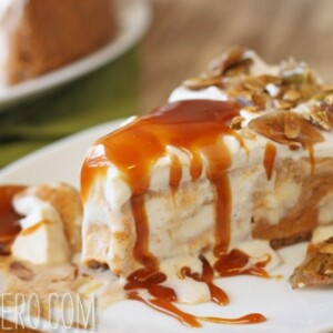 A slice of Pumpkin Ice Cream Pie on a white plate that is drizzled with caramel sauce and pumpkin brittle.