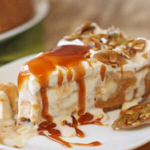 A slice of Pumpkin Ice Cream Pie on a white plate drizzled with caramel and pepita brittle.