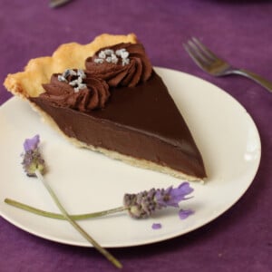 A slice of Chocolate Lavender Pie on a white plate next to lavender.