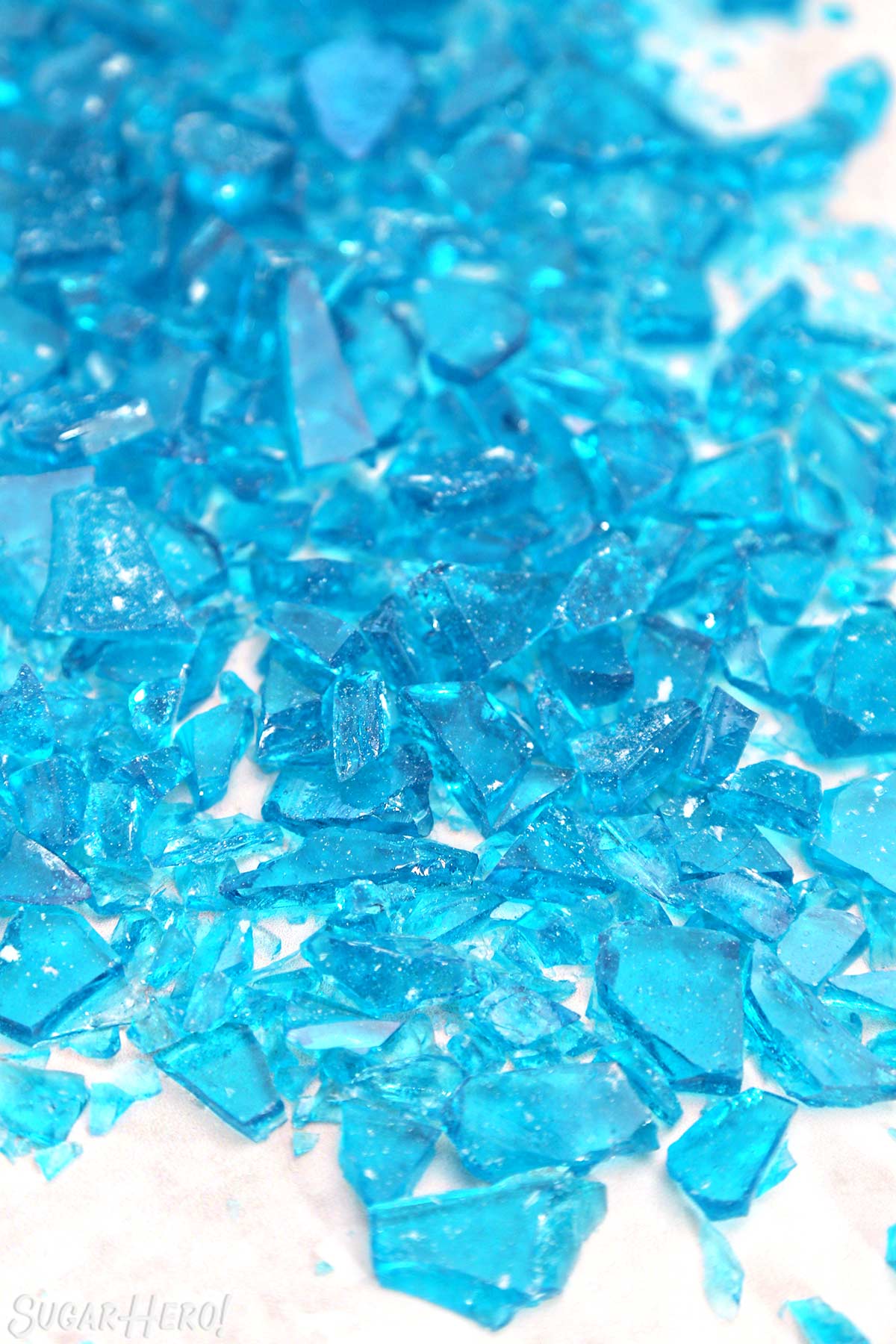 Plastic baggie of crumbled blue crystal meth rock candy surrounded by chunks of candy on a wooden surface.