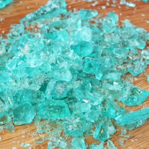 Small pieces of blue crystal meth rock candy on a wooden surface.