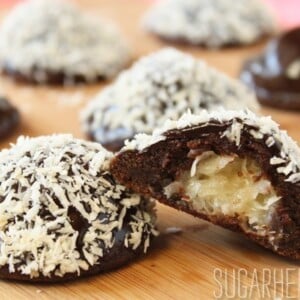 Mounds Cookies on a wooden surface with one cookie cut open to show filling.