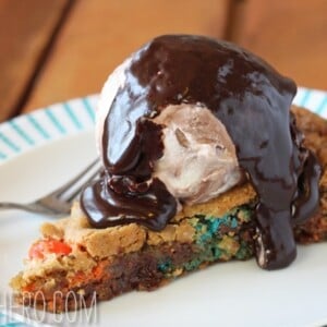 A slice of M&M Skillet Cookie covered with a scoop of ice cream and hot fudge.