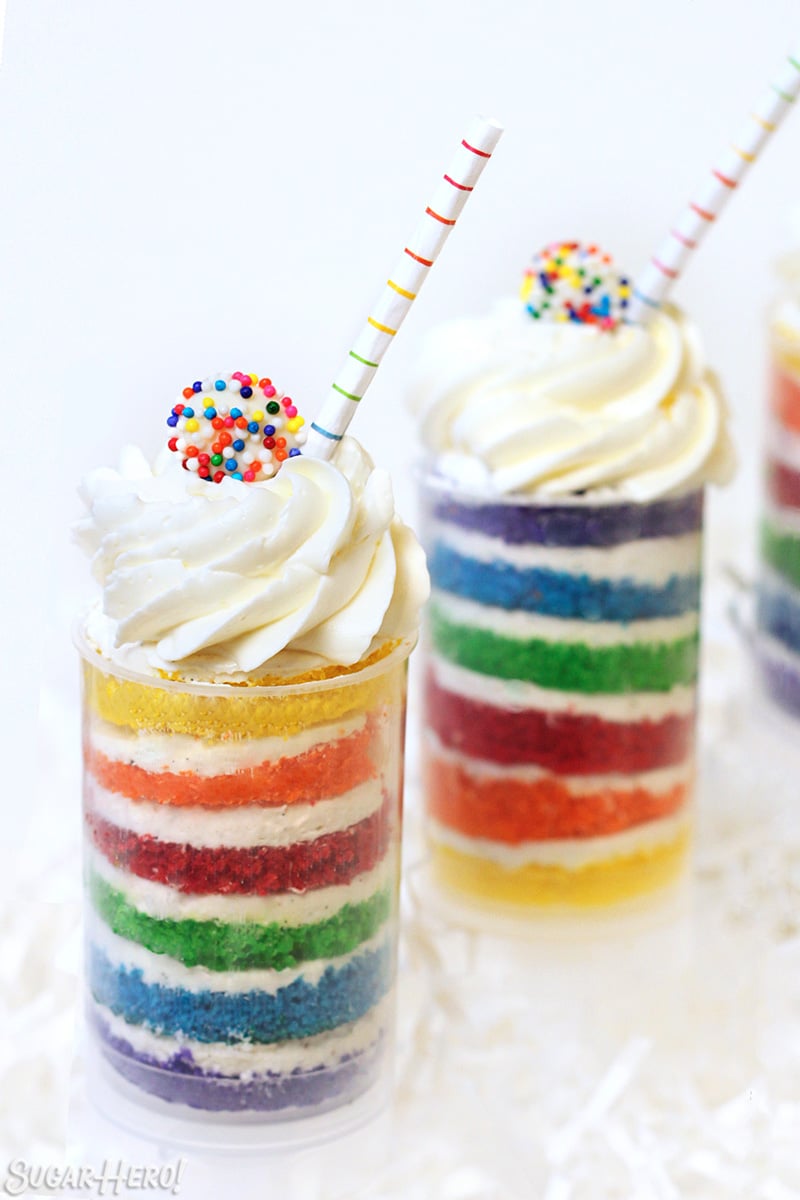 Three Rainbow Cake Push-Up Pops in front of a white background with striped straws sticking out.