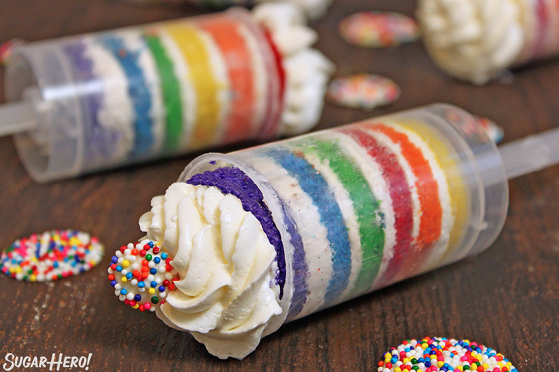 Close-up of two Rainbow Cake Push-Up Pops on a wooden surface.
