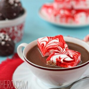 2 Peppermint Swirl Marshmallows in a cup of hot chocolate with hot chocolate truffles in the background.