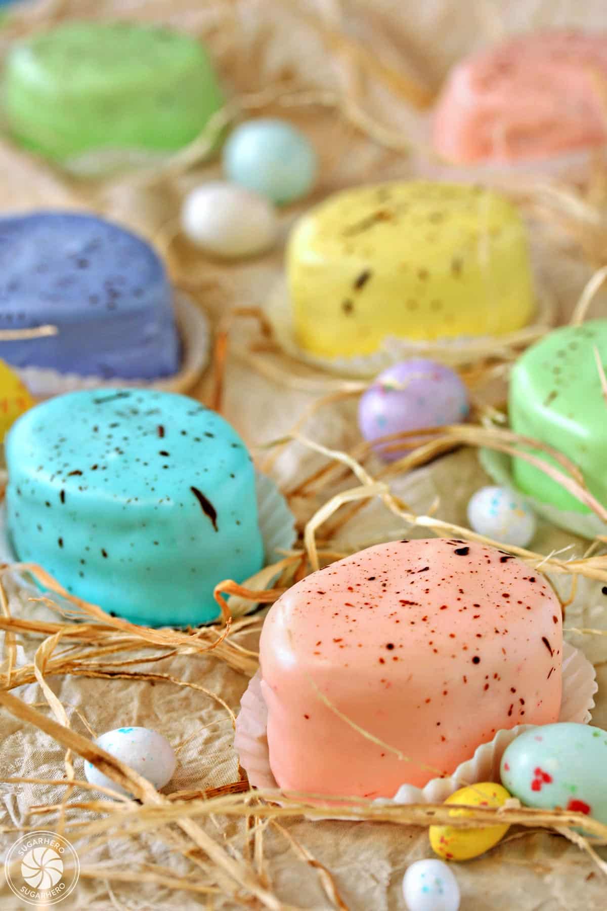 Looking for a gorgeous Easter dessert? Try these Easter Egg Petit Fours! They're sweet mini cakes with a pretty pastel speckled glaze | From SugarHero.com Easter Egg Petit Fours - assortment of pastel petit fours that look like speckled Easter eggs | From SugarHero.com