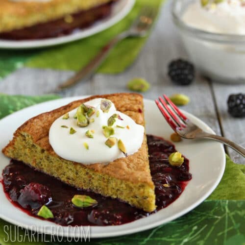 Slice of Pistachio Cake with Blackberry Sauce on a white plate.