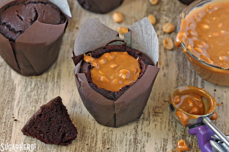 Snickers Cupcakes - In these Snickers Cupcakes, plain chocolate cupcakes are transformed into decadent, candy-bar inspired creations, featuring a peanut caramel filling, fluffy peanut butter frosting, and LOTS of chocolate and candy bars. | From SugarHero.com Snickers Cupcakes - A shot of the cupcake filled with caramel sauce and peanuts. | From SugarHero.com