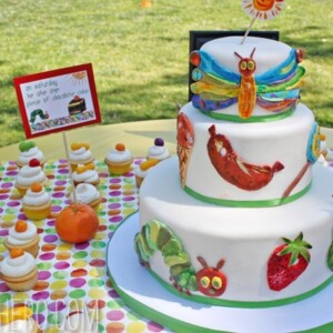 Very Hungry Caterpillar Cake on a table with cupcakes.
