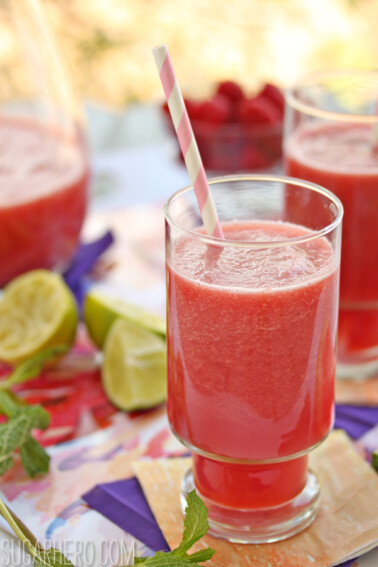 Close up of a glass of Watermelon-Raspberry Juice with a straw in it.