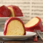 Slice of Cream Cheese Cake with Red Velvet Fudge Frosting on a white plate.