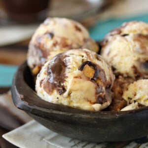 Several scoops of Almond Coconut Fudge Ripple Ice Cream in a dark colored bowl.