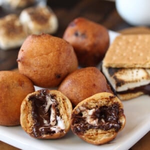 A pile of Deep Fried S'mores on a white plate with the front s'more cut open to show melty inside.