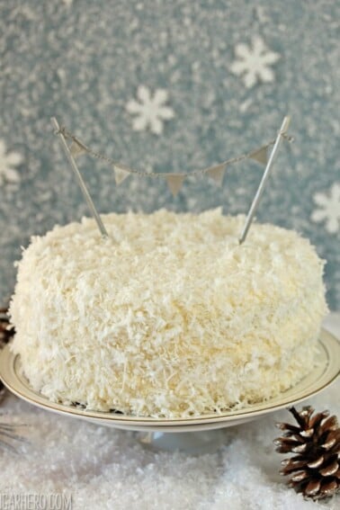 A Coconut Layer Cake on a white cake plate.
