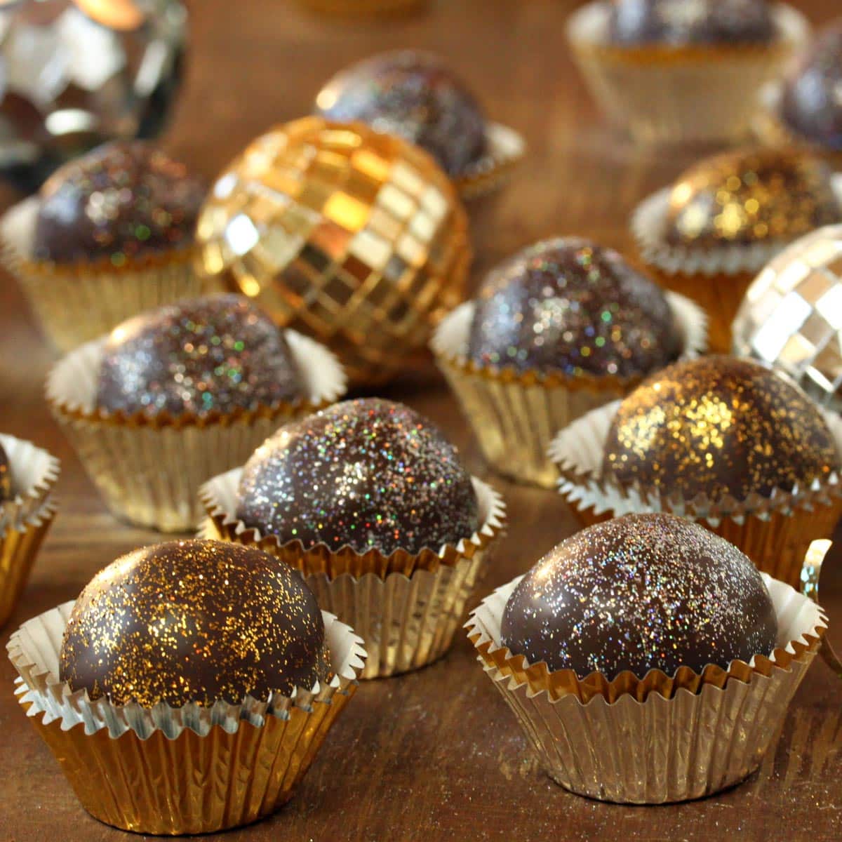 Several Disco Truffles in gold wrappers next to a disco ball.