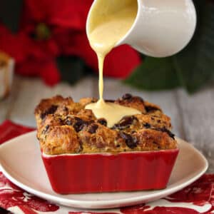 Pannetone Bread Pudding in a red ramekin with sauce on top.