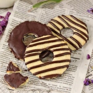 Close up of 3 Fudge Striped Shortbread Cookies on a piece of newspaper.