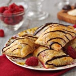 Close up of 4 Raspberry Brie and Chocolate Puff Pastries on a floral plate on a red napkin.
