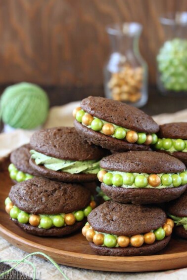 A pile of Mint Chocolate Chip Whoopie Pies on a wooden platter.
