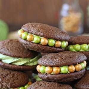 A pile of Mint Chocolate Chip Whoopie Pies on a wooden platter.