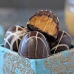 Teal and gold box of Caramelized White Chocolate Truffles with bite taken out of top truffle.