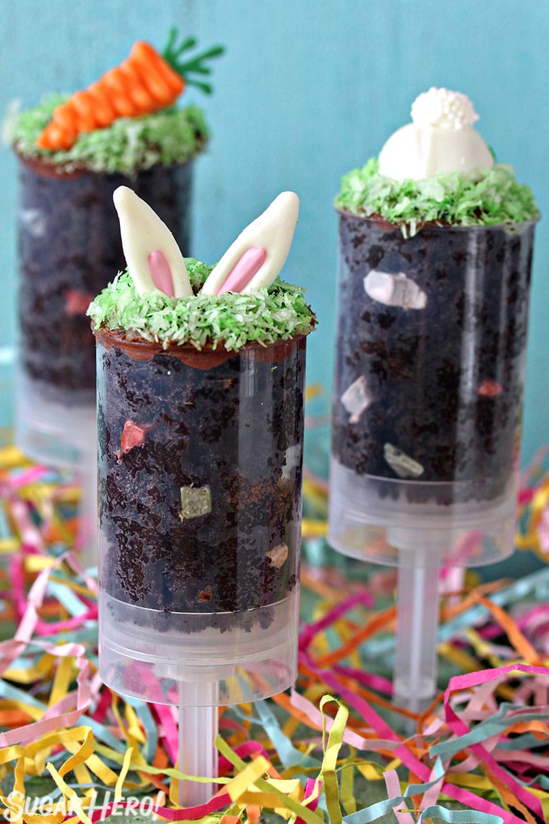 Three Easter push-up pops filled with chocolate cake and topped with bunny ears, a bunny butt or a chocolate carrot.