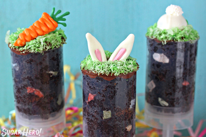 Three Easter push-up pops filled with chocolate cake and topped with bunny ears, a bunny butt or a chocolate carrot.