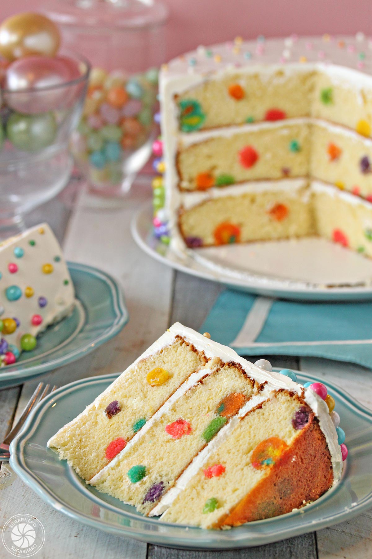 Easter Polka Dot Cake - A slice of the polka dot cake, displaying full cake in background. | From SugarHero.com