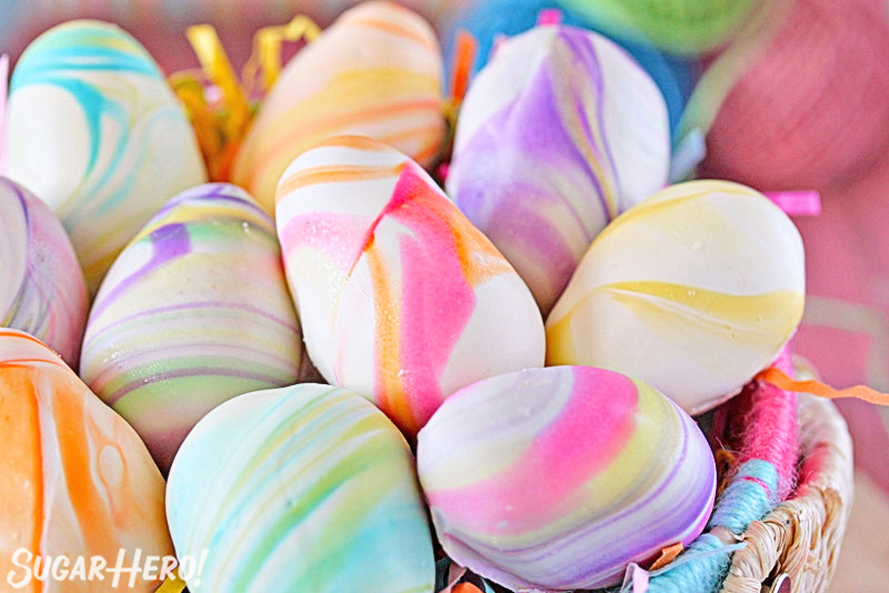 Close-up of white chocolate truffles with pastel swirl decorations.