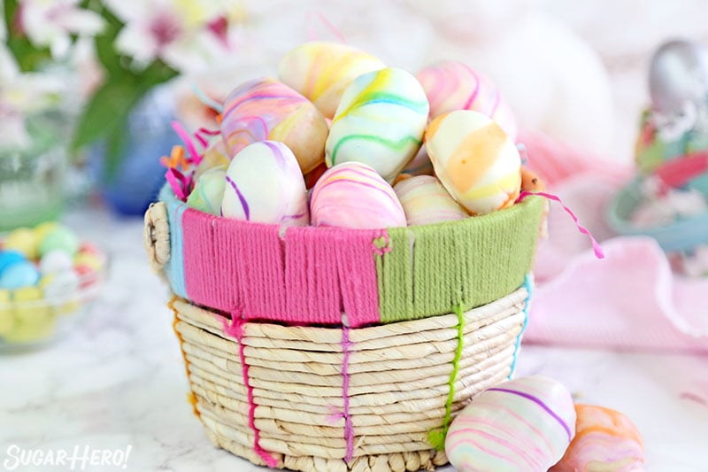 Marbled Easter Egg Truffles in a woven Easter basket on a white marble surface.