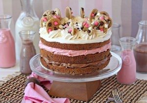 Neapolitan Chocolate Chip Cookie Cake on a cake platter with colorful chocolate milk in the background.