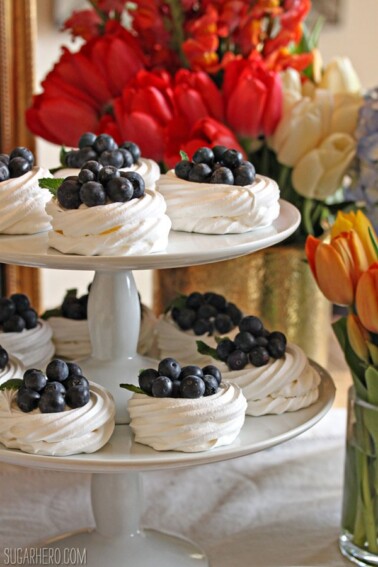 Blueberry Pavlovas on a two-tier platter with tulips in the background.