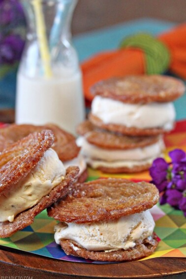 2 Churro Ice Cream Sandwiches stacked off center on a brightly colored napkin next to purple stock.