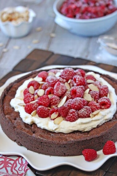 Close up of a Chocolate Raspberry Almond Truffle Tart on a white platter.