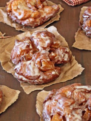 Apple Cider Fritters cooling on brown paper.