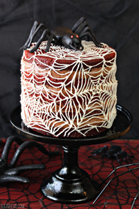 Spiderweb Naked Red Velvet Cake on a black cake stand on a black and red table.