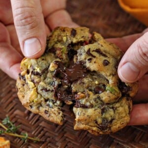 Close up of a hand breaking a Clemen-Thyme Chocolate Chunk Cookie.