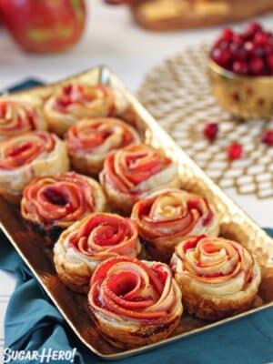 Baked Apple Cranberry Gouda Puff Pastry Roses on a baking tray with cranberries and apples in the background.